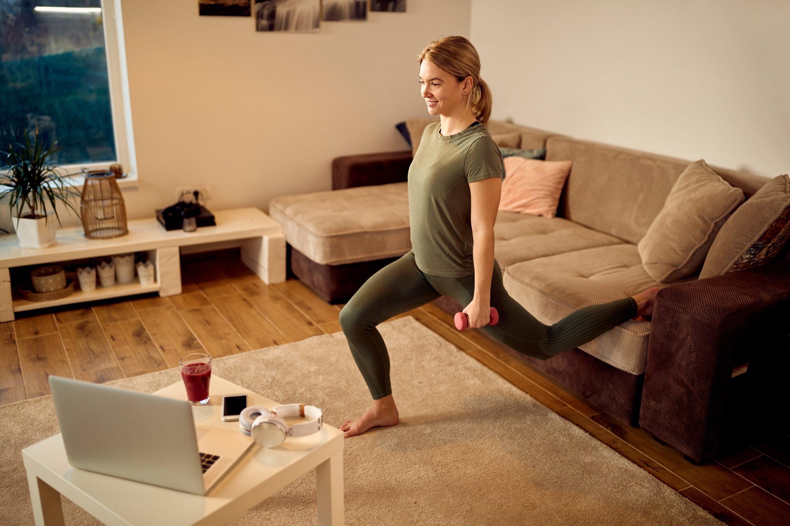 Happy athletic woman using dumbbells while exercising in the living room.